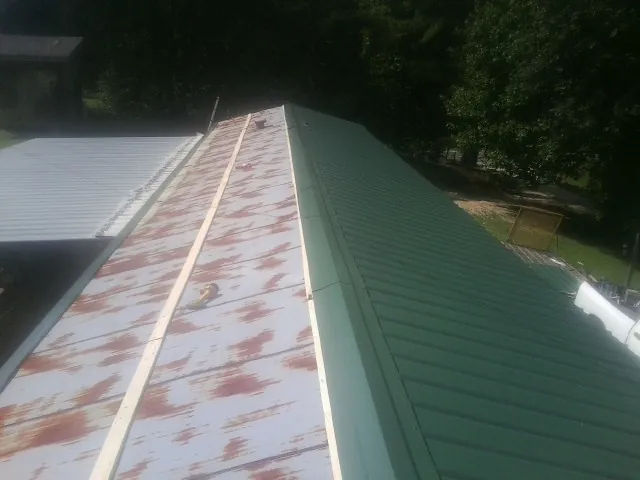 Old rusted panels beside newly installed green metal roofing — Wind Damage Roof Repair by Roofing Brothers in Zolfo Springs