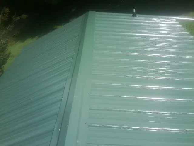 New green metal panels meeting at the ridge of a roof — Flat Roof Repair work by our crew in Zolfo Springs