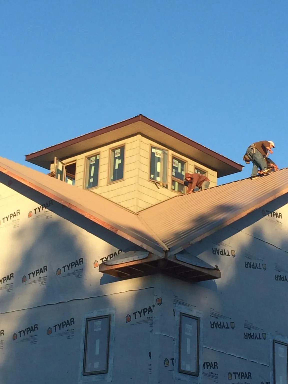 Roofers working around a rooftop cupola on a new metal roof at sunset — Roof Waterproofing in Zolfo Springs by Roofing Brothers